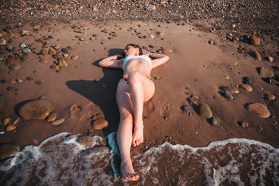 High angle view of young woman on rock at beach