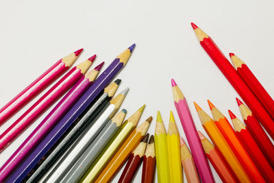 High angle view of colored pencils against white background