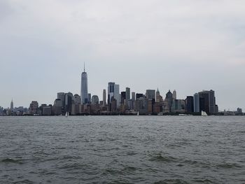 Sea by modern buildings against sky in city