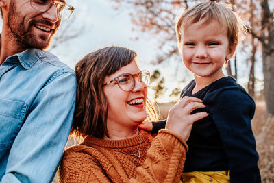 Smiling parents tickling young son outside on a fall evening