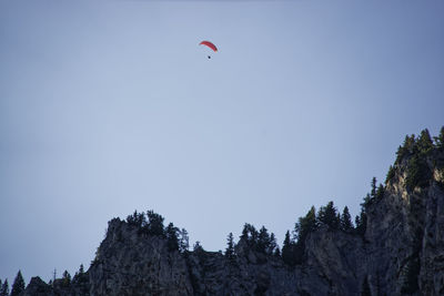 Low angle view of people flying against clear sky