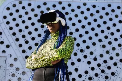 Woman wearing sunglasses standing against wall