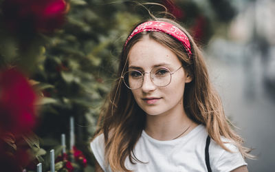 Close-up portrait of young woman standing by plants