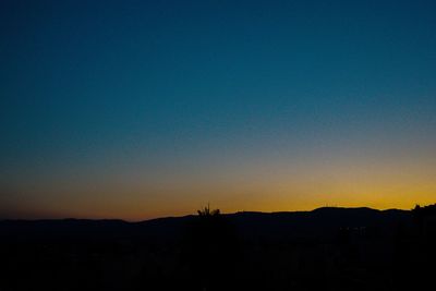 Silhouette landscape against clear sky at sunset