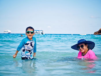 Portrait of boy smiling in sea against sky