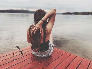 Rear view of woman sitting by lake