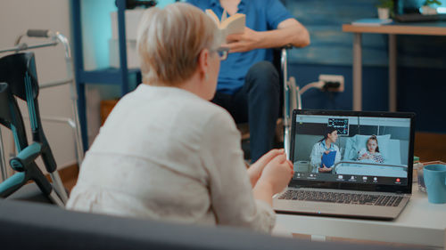 Rear view of woman doing video call on laptop