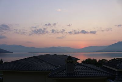 Houses by sea against sky during sunset