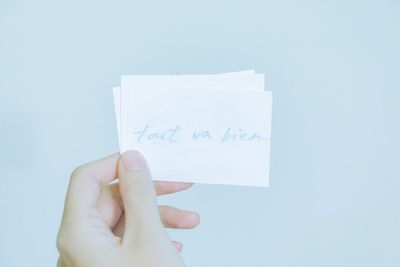 Close-up of hand holding paper against white background