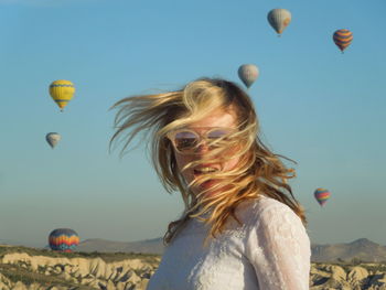 Young happy woman with balloons against sky