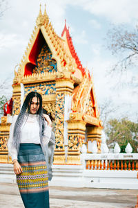 Portrait of young woman standing on temple against building