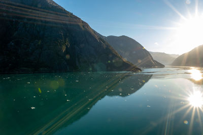 Scenic view of lake against sky with sun reflecting water - endicott arm fjord 