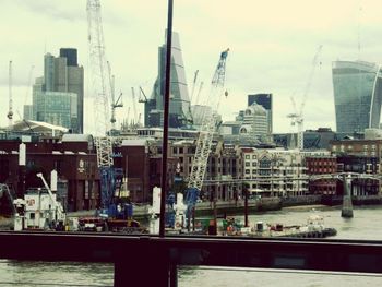 Modern buildings by river against sky in city