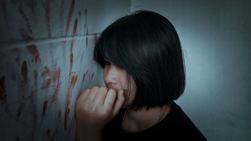 Woman looking away by blood on wall