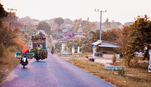 Street amidst buildings and trees against sky
