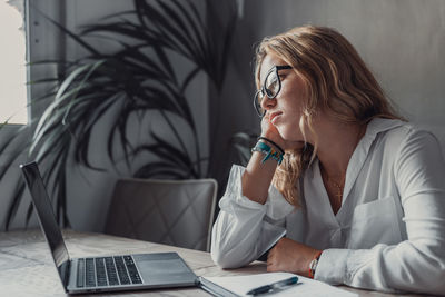 Businesswoman using laptop while sitting on table