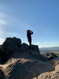 Man standing on rock against sky