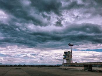 Lighthouse on landscape against storm clouds