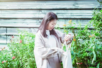 Portrait of young woman standing against plants