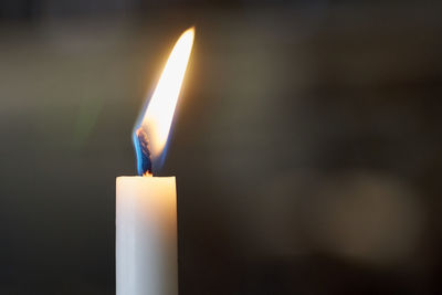 Close-up of burning candle in darkroom