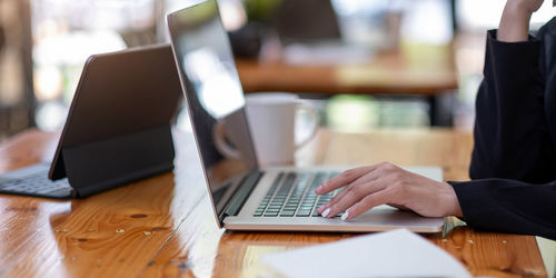 Midsection of woman using laptop on table