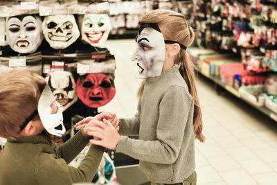 The kids chooses the masks at a store for halloween