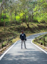 Rear view of man walking on road in forest