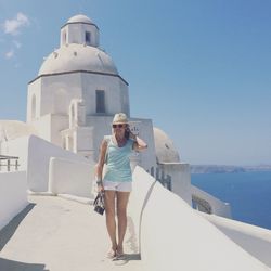 Full length of happy woman standing against built structure at santorini