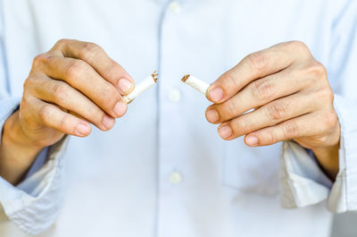 Midsection of man breaking cigarette 