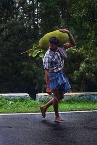Rear view of guy standing on road against trees