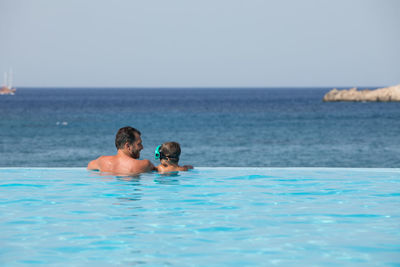 Rear view of couple at sea against sky