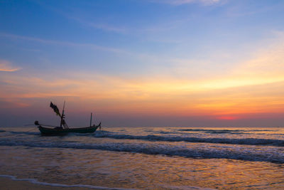 Silhouette people in sea against sky during sunset