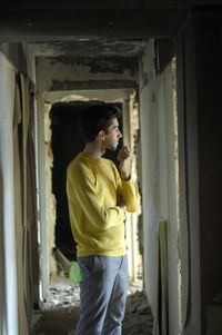 Side view of man standing in abandoned corridor