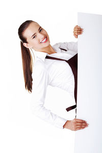 Portrait of smiling young woman wearing apron while holding placard against white background