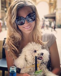 Portrait of smiling young woman sitting with dog at outdoor cafe