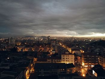 Aerial view of illuminated cityscape against dramatic sky