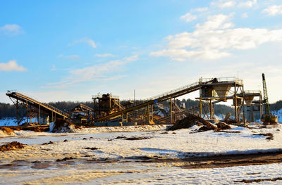 View of abandoned cars on snow covered land against sky