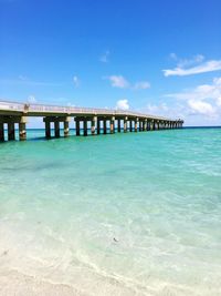 Pier over sea against blue sky