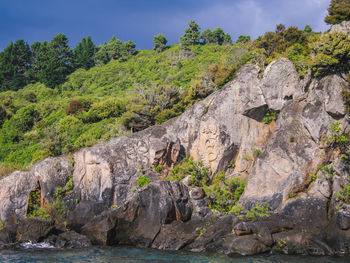 Scenic view of rocks by sea against sky