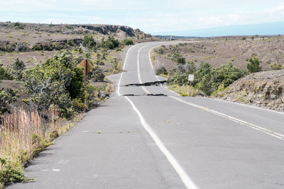 Broken from earthquake road passing through landscape against sky