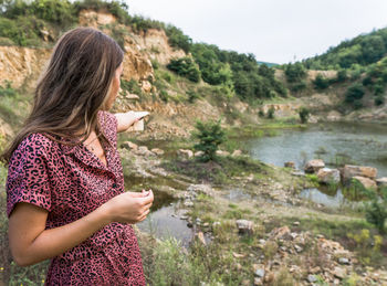 Side view of young woman standing by lake