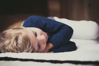 Close-up of small boy sleeping on bed at home.