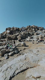 People on rock formations against clear blue sky