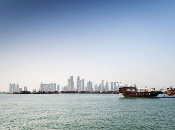 Sea by buildings against clear sky