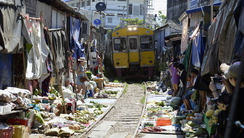 Train passing through vegetable market during sunny day