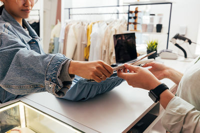 Midsection of woman holding smart phone at store