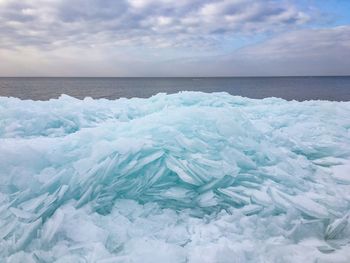 Close-up of ice by sea against cloudy sky