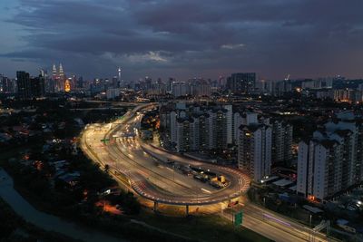 Aerial view of cityscape against cloudy sky at night