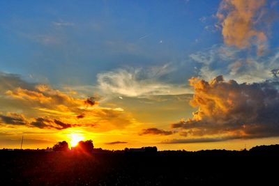 Silhouette landscape against dramatic sky during sunset