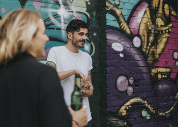 Young man standing against graffiti wall